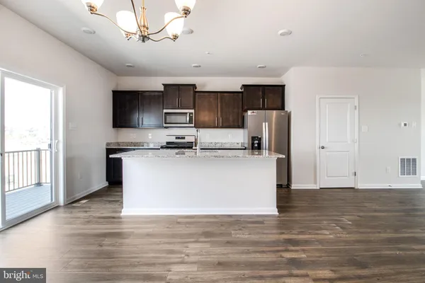 a view of kitchen with stainless steel appliances granite countertop a stove top oven a refrigerator a sink and dishwasher with wooden floor