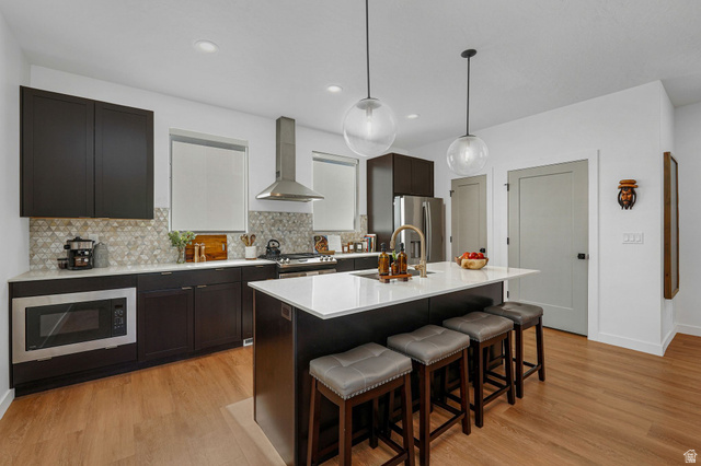 493 East Alice Way Layton, UT 84041 - Photo 3 of 31 Kitchen featuring light wood-type flooring, stainless steel appliances, hanging light fixtures, and a breakfast bar area