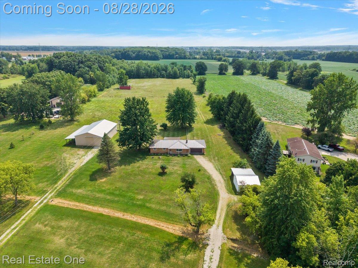 15250 34 Mile Road Armada, MI 48005 - Photo 13 of 49 Expansive property featuring multiple structures, mature trees, open fields, and a gravel drive