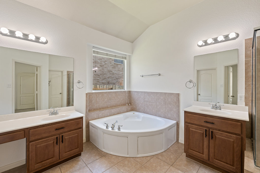 2617 Salorn Way Round Rock, TX 78681 - Photo 14 of 40 a bathroom with a tub a double vanity sink a window and a mirror