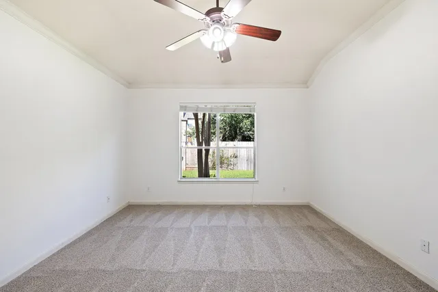 an empty room with a window and a ceiling fan