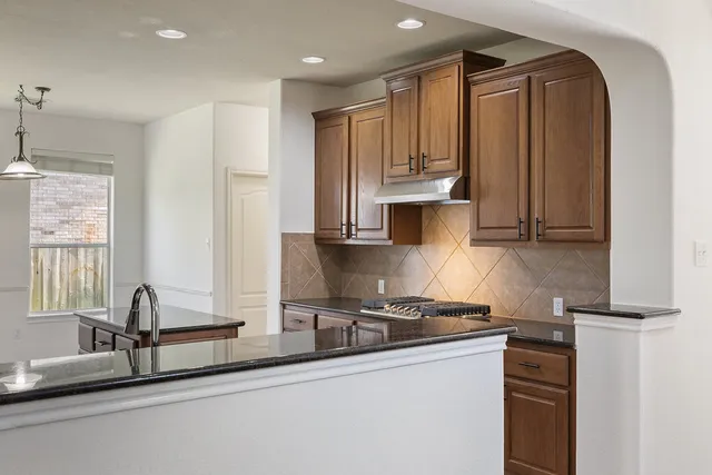 a kitchen with stainless steel appliances granite countertop a sink a stove and a refrigerator