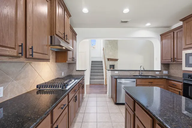 a kitchen with stainless steel appliances granite countertop a sink stove and cabinets