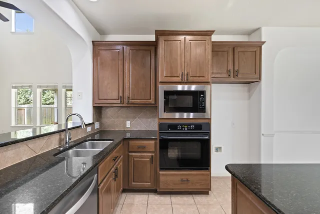 a kitchen with stainless steel appliances granite countertop a stove a sink and a microwave