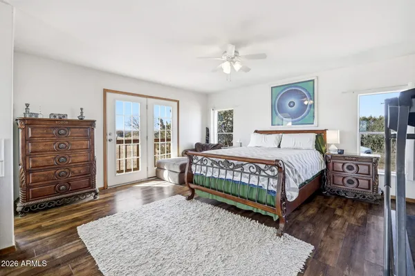 a bedroom with a bed a dresser and wooden floor