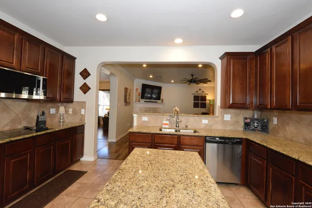 a large kitchen with kitchen island granite countertop a sink dishwasher stove and cabinets