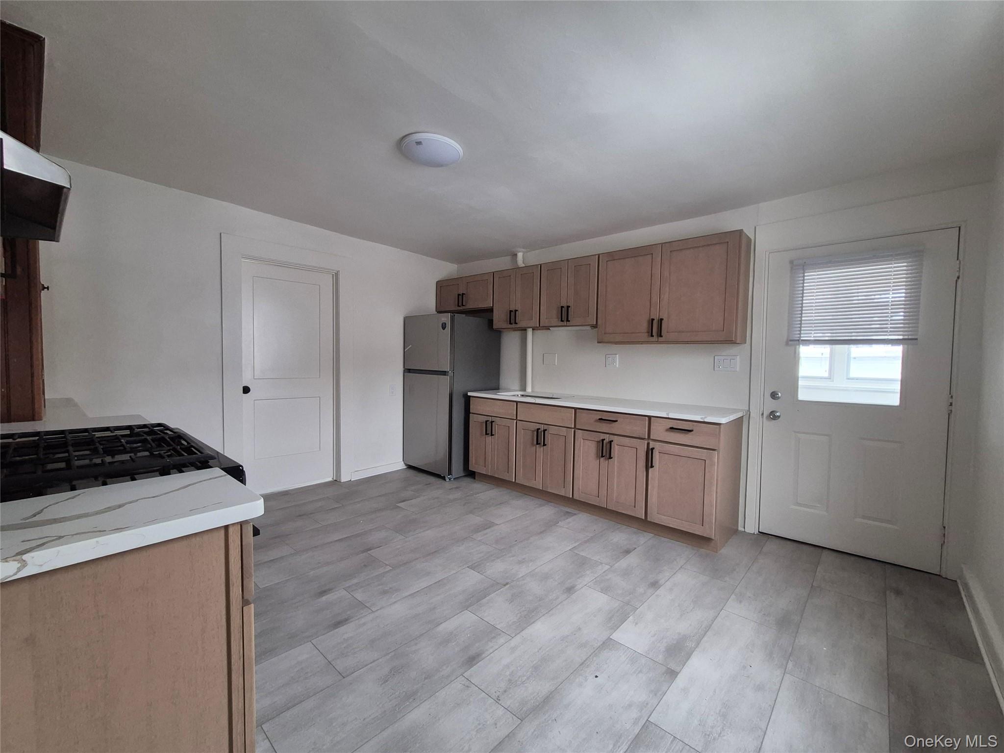 207 Mill Street Poughkeepsie, NY 12601 - Photo 3 of 6 Kitchen featuring freestanding refrigerator, wood finish cabinetry, and exhaust hood