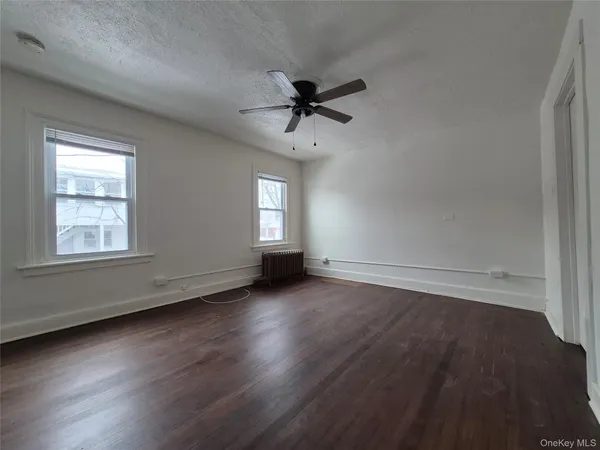 an empty room with wooden floor fan and windows