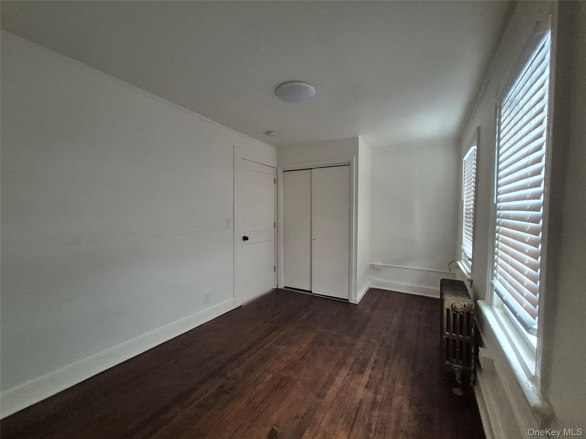 207 Mill Street Poughkeepsie, NY 12601 - Photo 6 of 6 Unfurnished bedroom with dark wood finished floors, radiator, and a closet