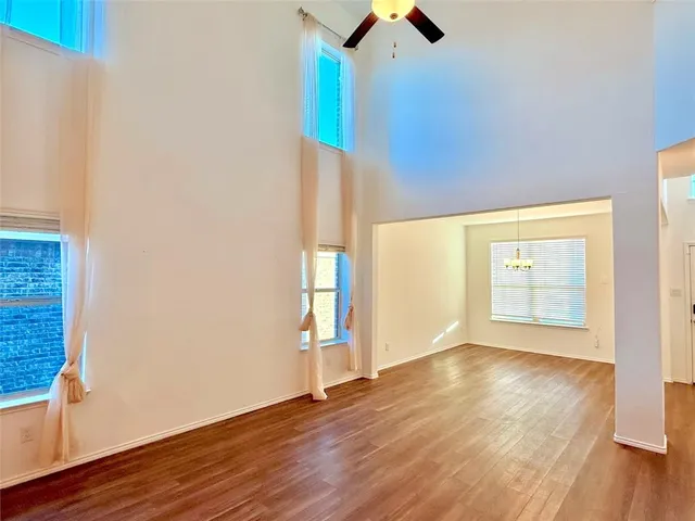 an empty room with wooden floor cabinet and windows
