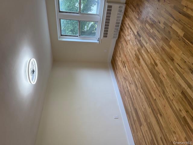 250 West Merrick Road, Unit 2R Freeport, NY 11520 - Photo 7 of 25 Spare room featuring wood finished floors and radiator heating unit