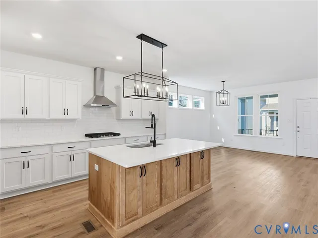 a kitchen with stainless steel appliances granite countertop a sink a stove and a wooden floors