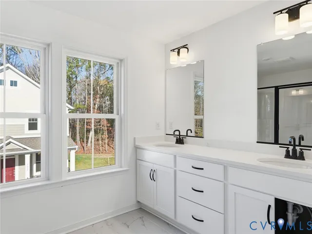 a bathroom with double vanity sink a window and a mirror