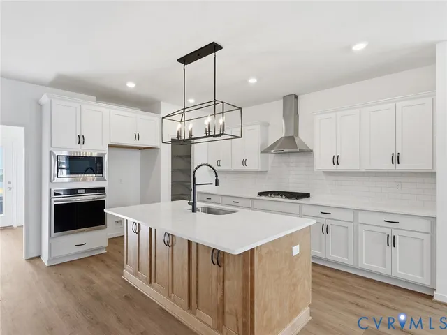 a kitchen with stainless steel appliances a sink a stove a refrigerator and white cabinets