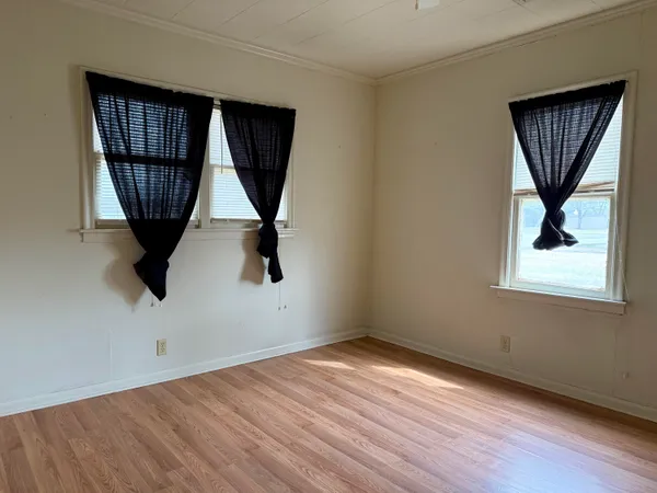 an empty room with a window and wooden floor
