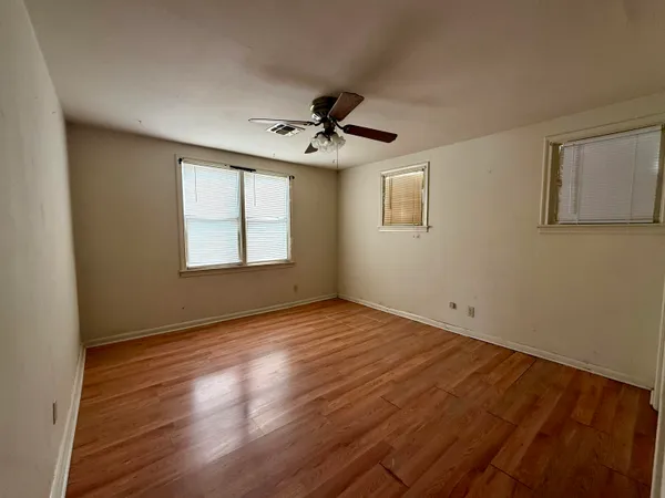 a view of an empty room with a window and wooden floor