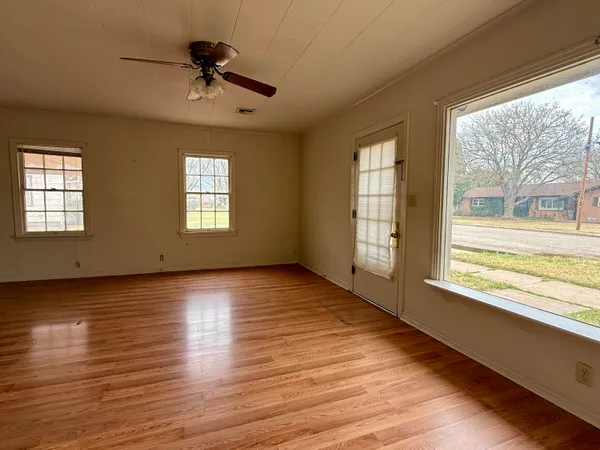 a view of an empty room with a window and wooden floor