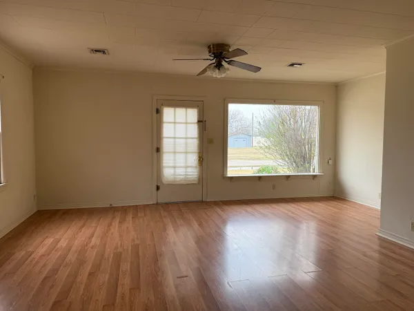 a view of an empty room with wooden floor and a window