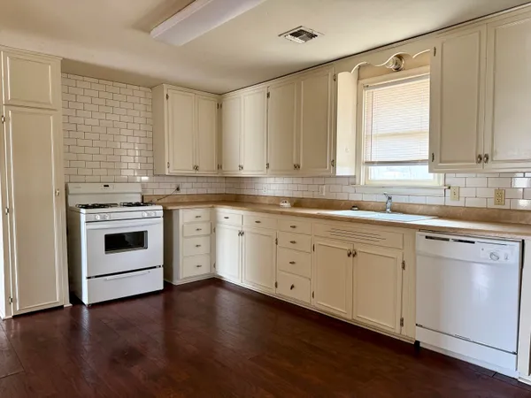 a kitchen with cabinets stainless steel appliances a sink and wooden floor
