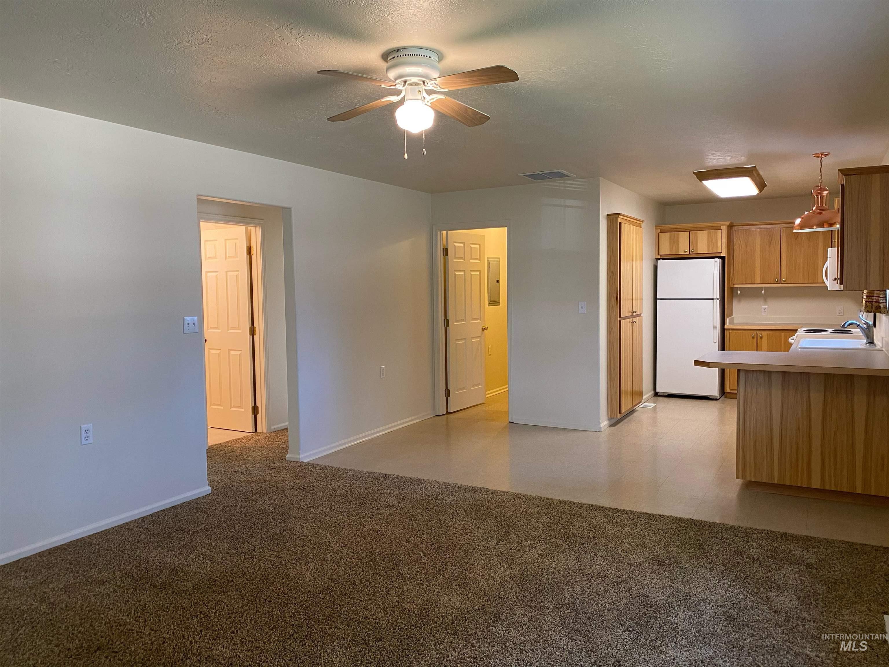 109 Adams Street Horseshoe Bend, ID 83629 - Photo 4 of 13 Unfurnished living room with a ceiling fan, a textured ceiling, and light carpet