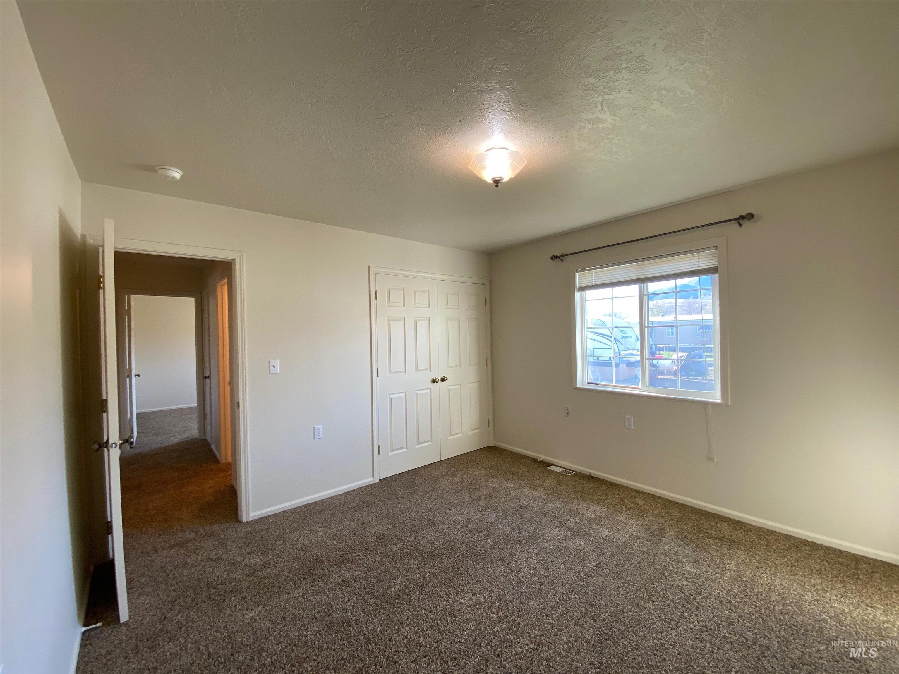 109 Adams Street Horseshoe Bend, ID 83629 - Photo 7 of 13 Unfurnished bedroom with dark carpet, a textured ceiling, and a closet