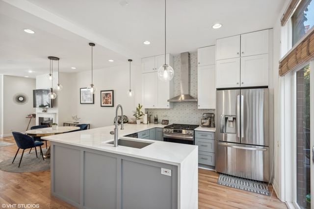 a kitchen with stainless steel appliances granite countertop a sink a stove a refrigerator and island with wooden floor