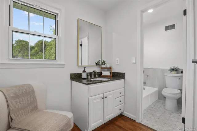 a bath room with a toilet a sink and a window