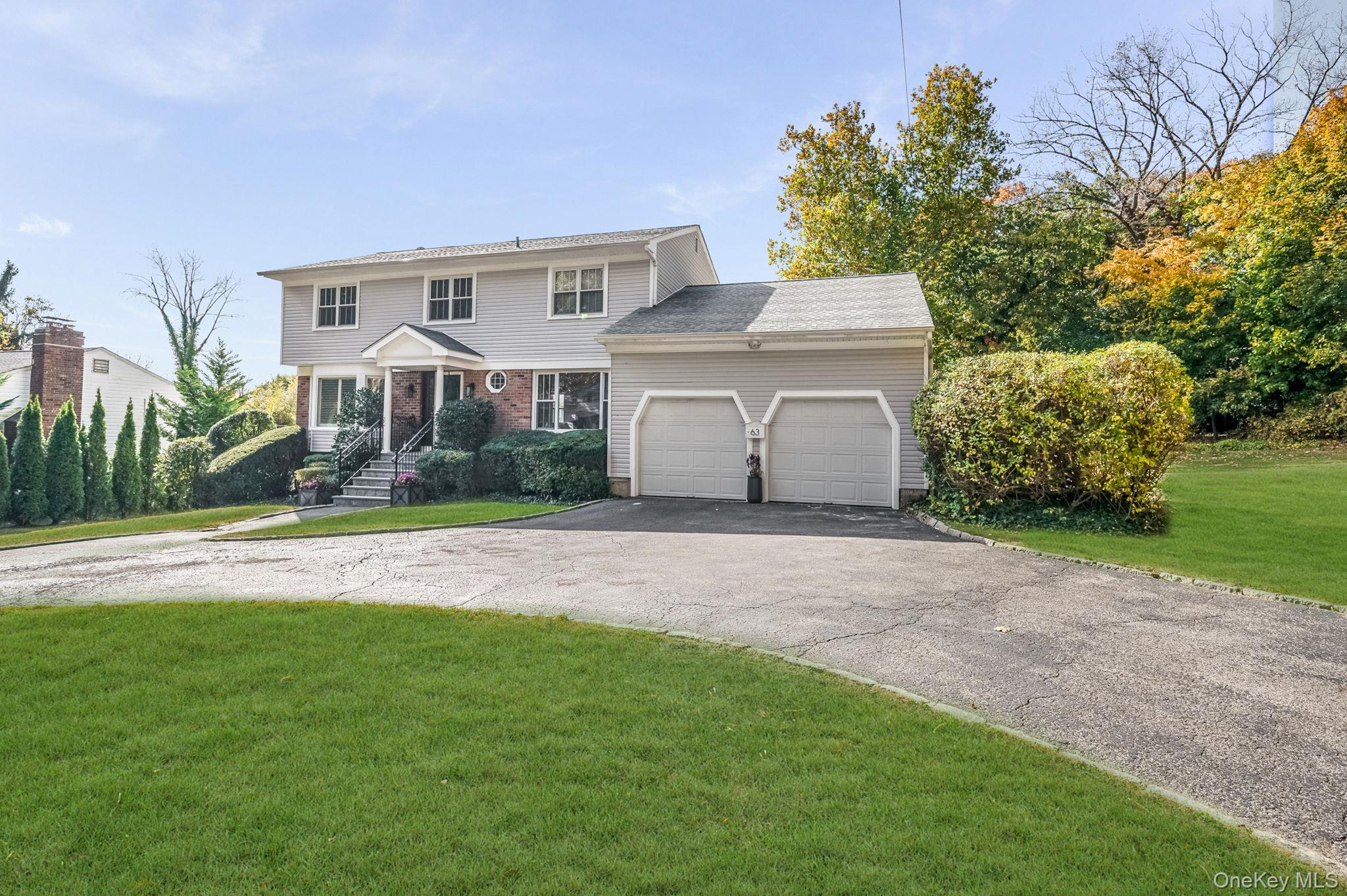 63 Underhill Road Scarsdale, NY 10583 - Photo 2 of 36 Front of property featuring a semi-circular driveway, 2-car garage, and the front lawn