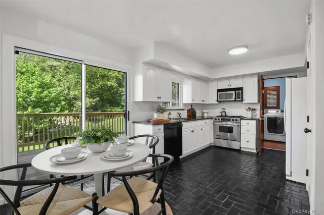 a kitchen with stainless steel appliances kitchen island a table chairs and a refrigerator