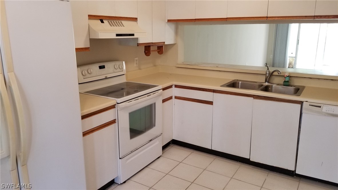 5665 Whitaker Road, Unit A101 Naples, FL 34112 - Photo 17 of 17 a kitchen with white cabinets appliances and sink