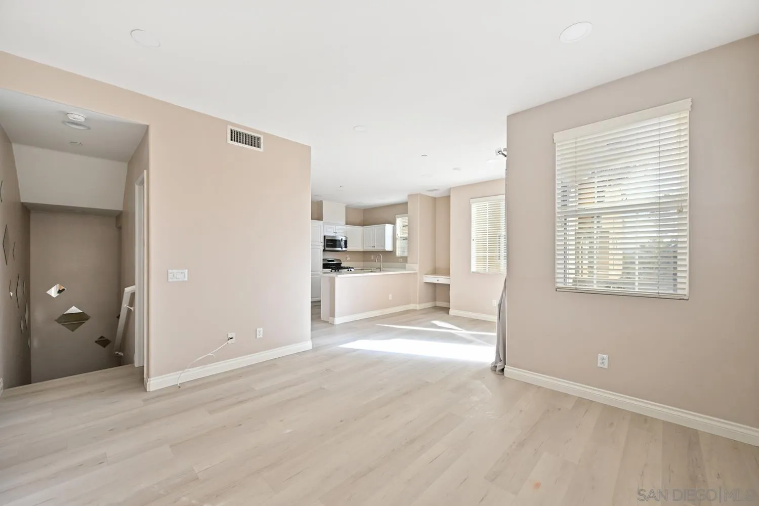 5074 Cascade Way, Unit 102 Oceanside, CA 92057 - Photo 3 of 30 a view of a kitchen and an empty room with wooden floor and a window