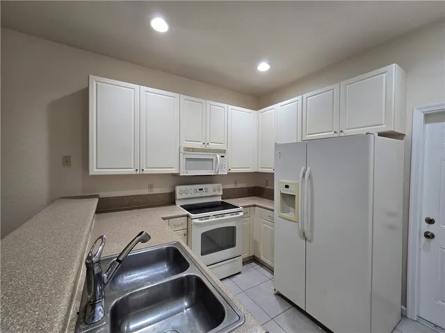 a kitchen with a refrigerator sink and cabinets