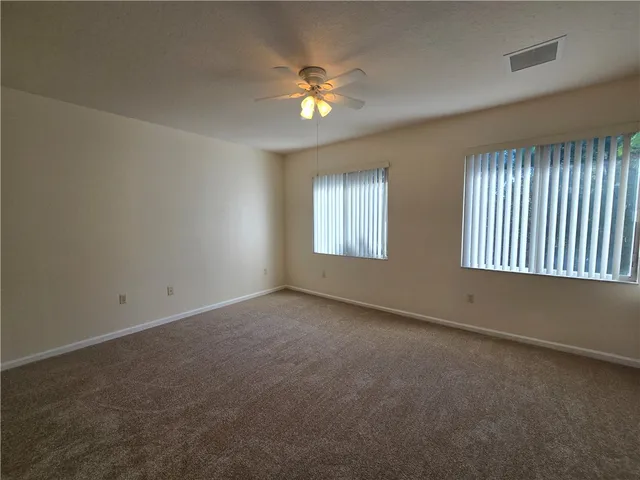 an empty room with windows and chandelier fan