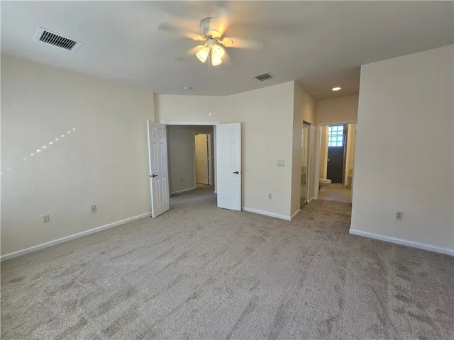 a view of a room with a ceiling fan and entryway