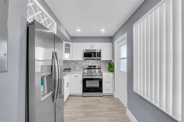 a kitchen with stainless steel appliances granite countertop a refrigerator and a stove top oven