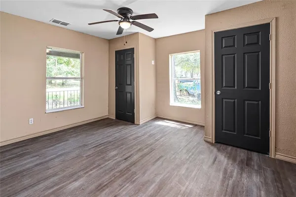 a view of an empty room with wooden floor and a window