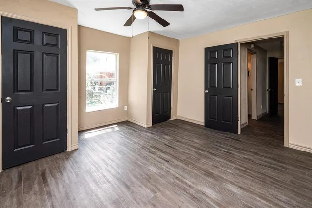 an empty room with wooden floor closet and windows