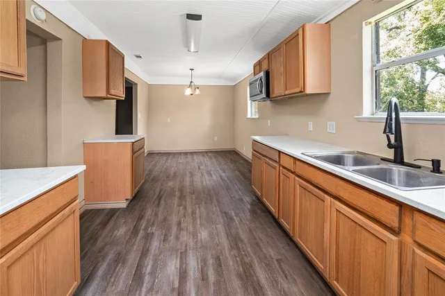 a kitchen with stainless steel appliances wooden floors wooden cabinets a sink and a window