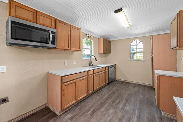 a kitchen with stainless steel appliances granite countertop a sink a microwave a stove and wooden floors
