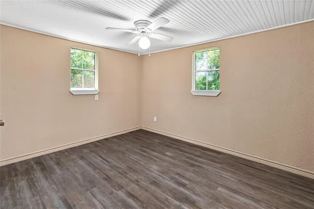 an empty room with windows and ceiling fan