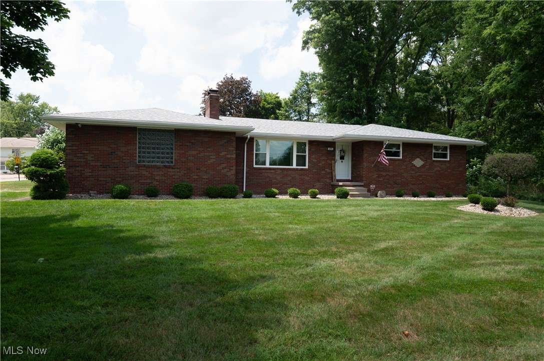 Single story home with brick siding, a chimney, and a front yard