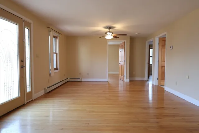 a view of an empty room with window and wooden floor