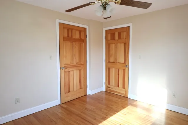 a view of empty room with wooden floor and fan