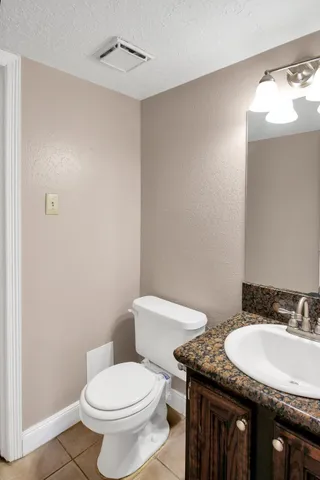 a bathroom with a granite countertop toilet a sink and a mirror