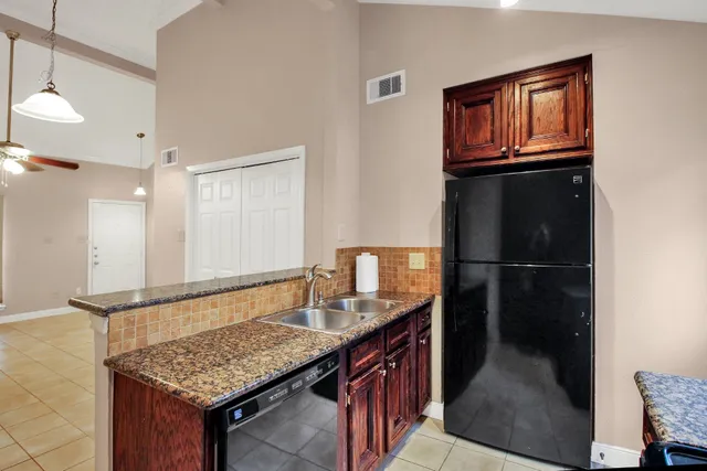 a kitchen with a granite countertop sink refrigerator and cabinets
