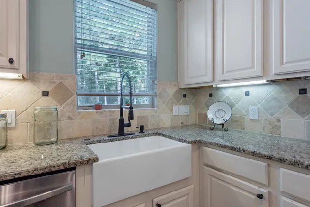 a kitchen with granite countertop a sink a stove and cabinets
