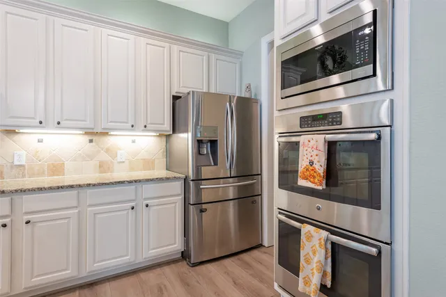 a kitchen with granite countertop white cabinets and stainless steel appliances