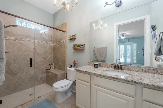 a bathroom with a granite countertop sink a toilet and shower