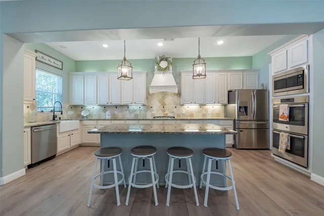 a kitchen with kitchen island granite countertop wooden floor and stainless steel appliances