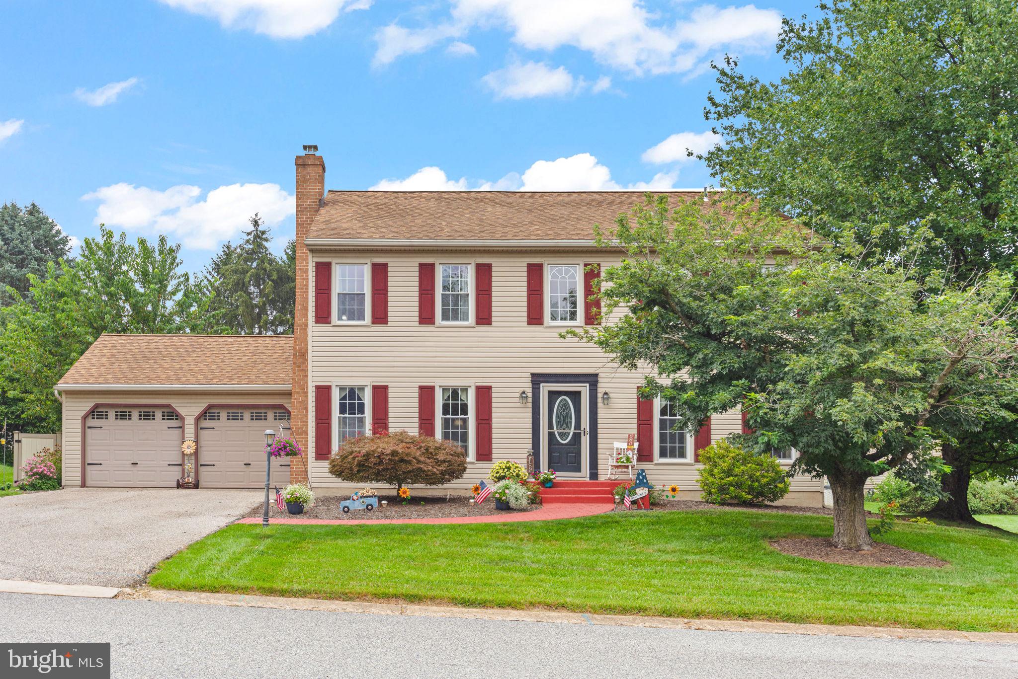 a front view of a house with a garden and tree